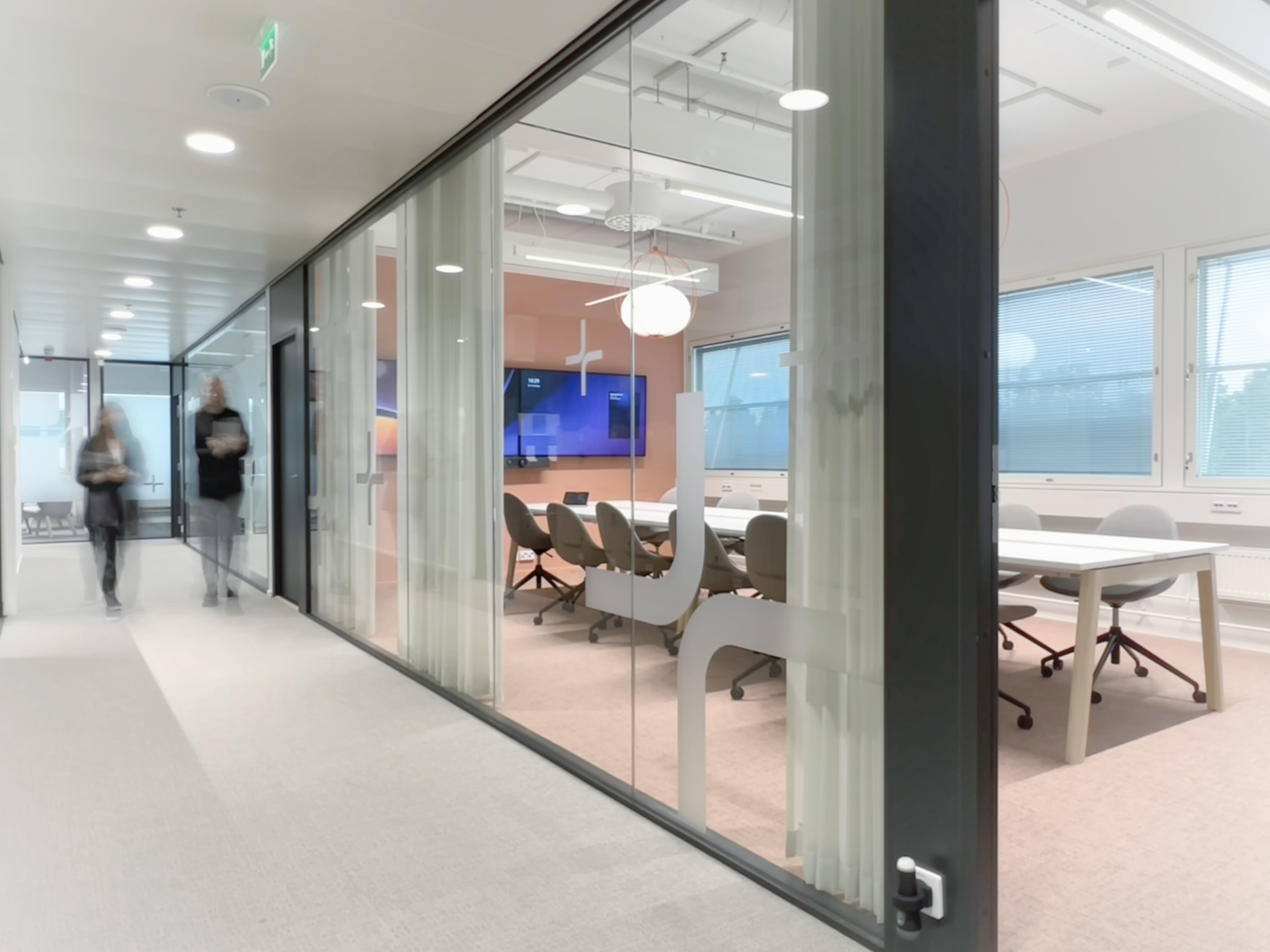 Colour photograph of the offie we designed for Figure. We see a meeting room with peach walls and carpet and fresh lighting.
